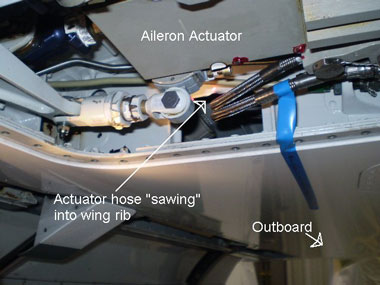 Aileron actuator hose sawing into wing rib.