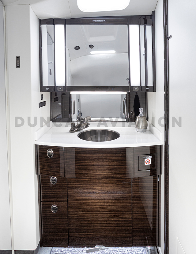 Interior refurbishment of lavatory with white counter and dark wood cabinet