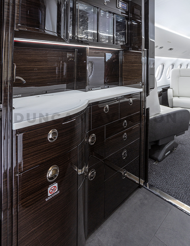 Dark wood galley of Falcon 2000 with white counter after interior refurbishment