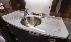 Lavatory sink with marble counter and dark wood cabinet in Falcon 900