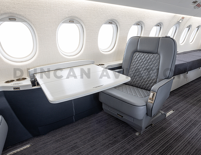 Gray club seat with white conference table in Falcon 2000