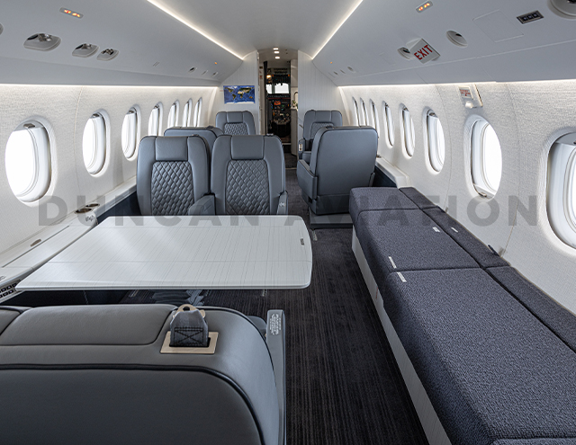 Interior of Falcon 2000 interior refurbishment with soft gray upholstery and conference table