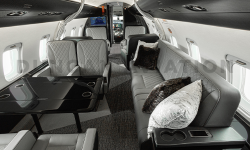 Interior of refurbished Challenger 604 with gray leather upholstered divan with accent pillows and club seat with conference table