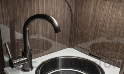Refurbished sink in galley of Falcon 900 with white counters, dark wood and burnished metal finish
