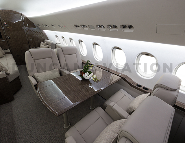 Seating with table on Falcon 900. Seats in cool beige leather and table in dark wood.