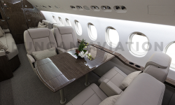 Seating with table on Falcon 900. Seats in cool beige leather and table in dark wood.