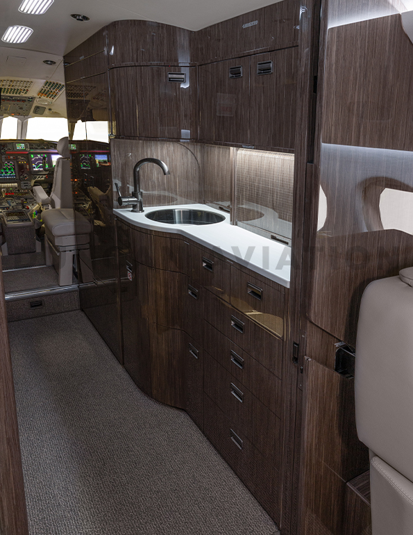 View of full galley in refurbished Falcon 900 with dark wood and white counter tops
