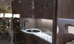 View of full galley in refurbished Falcon 900 with dark wood and white counter tops
