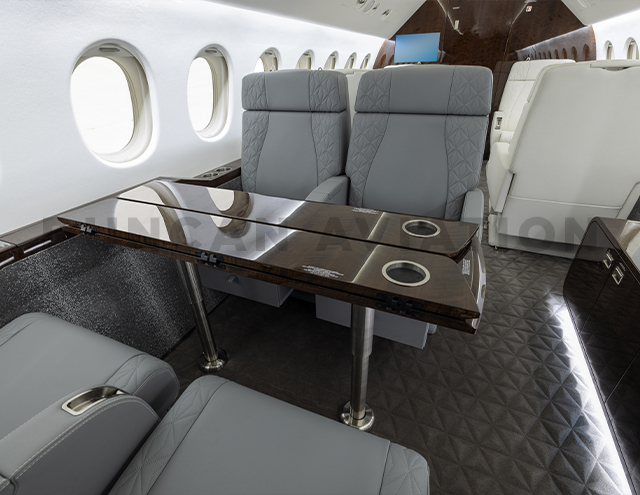 Gray leather seats with fold out dark wood table in Falcon 900
