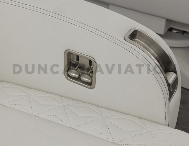 Close up of arm rest wrapped in white leather with brushed sliver seat levers