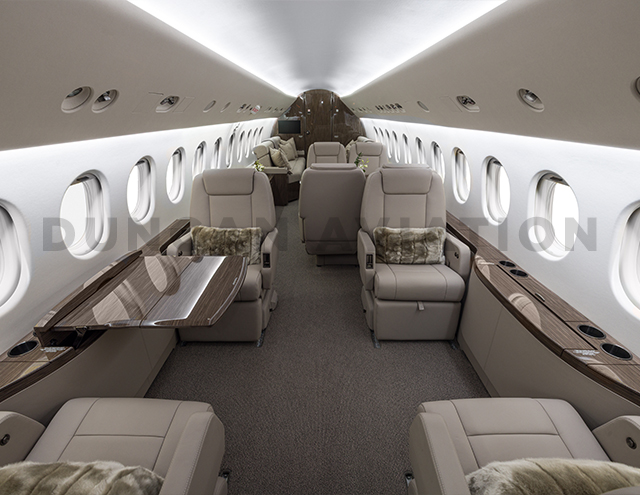 View of entire cabin of newly refurbished Falcon 900 with cool beige leather, dark brown carpet, and dark wood on drink rails