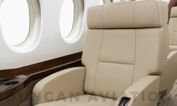 Close up of tan leather captain chair next to drink rail in Falcon 2000 refurbished by Duncan Aviation