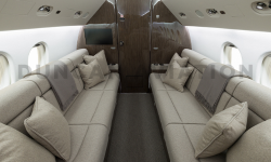 Two divans facing each other in cool beige leather with dark carpet and dark wood on Falcon 900 refurbished by Duncan Aviation
