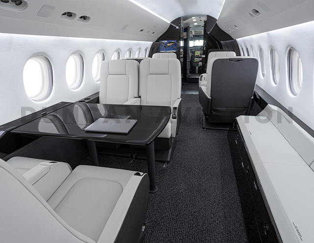 Interior refurbishment of Falcon 2000 with white leather club seats, conference table and credenza