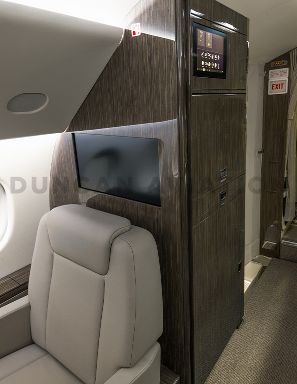 Interior of refurbished Falcon 900 with cool beige leather seats and dark wood.