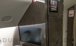 Interior of refurbished Falcon 900 with cool beige leather seats and dark wood.