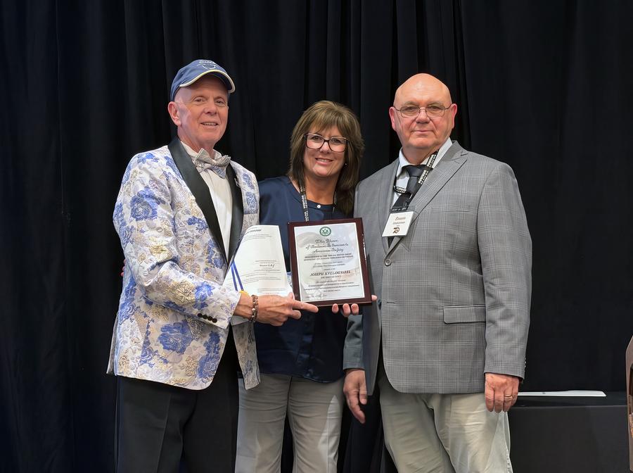 Joe Tulowitzki stands with his wife and an FAA member as he holds his Charles Taylor award certificate
