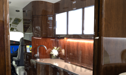 Galley in newly refurbished Falcon 2000 featuring dark wood tones and ample lighting