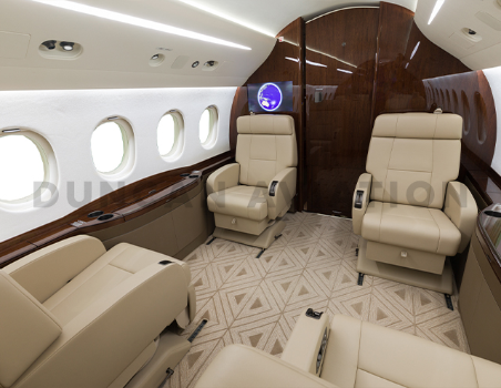 Interior of refurbished Falcon 2000 with tan geometric carpet, tan leather seats, and dark wood
