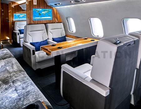 Double white leather seats with warm wood table in Global Express refurbished by Duncan Aviation