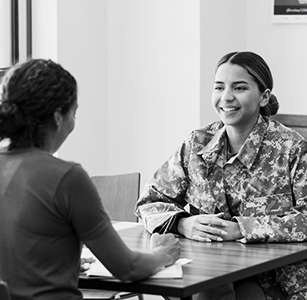 Two female soldiers seated at table having a discussion